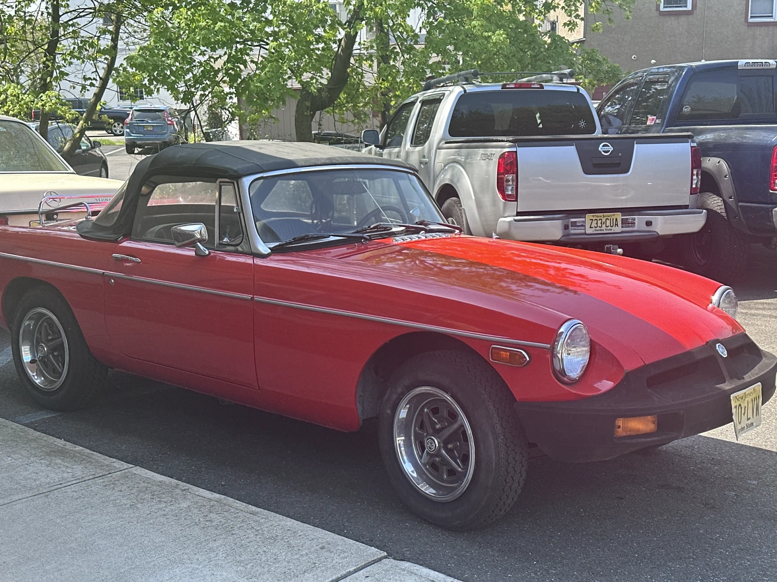 Red classic MG roadster parked near Checkered Flag Auto Service